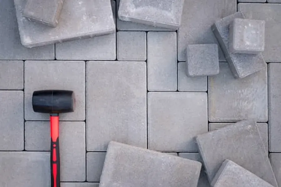 Concrete pavers laid in a running bond pattern with a rubber installation mallet resting on the surface