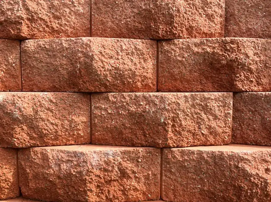 Stacked split-face block retaining wall with textured earth-tone units in tight running bond