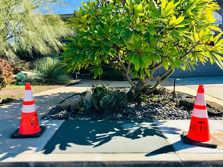 Freshly poured concrete driveway section curing behind safety cones in front of a Southern California home