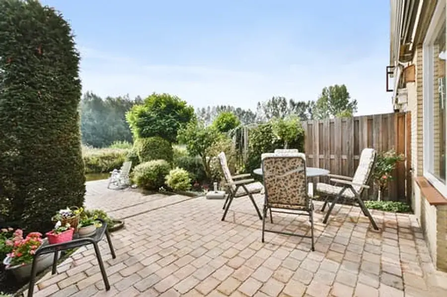 Finished backyard paver patio with outdoor seating, planters, and a wood privacy fence