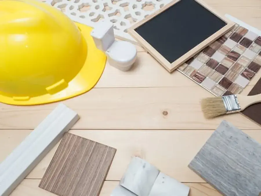 Construction hard hat surrounded by tile, stone, and flooring material samples on a workbench