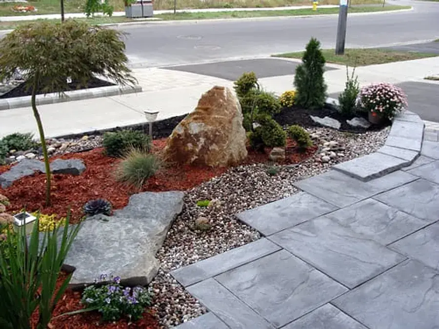 Finished gray slate-pattern stamped concrete walkway bordering a landscaped front yard